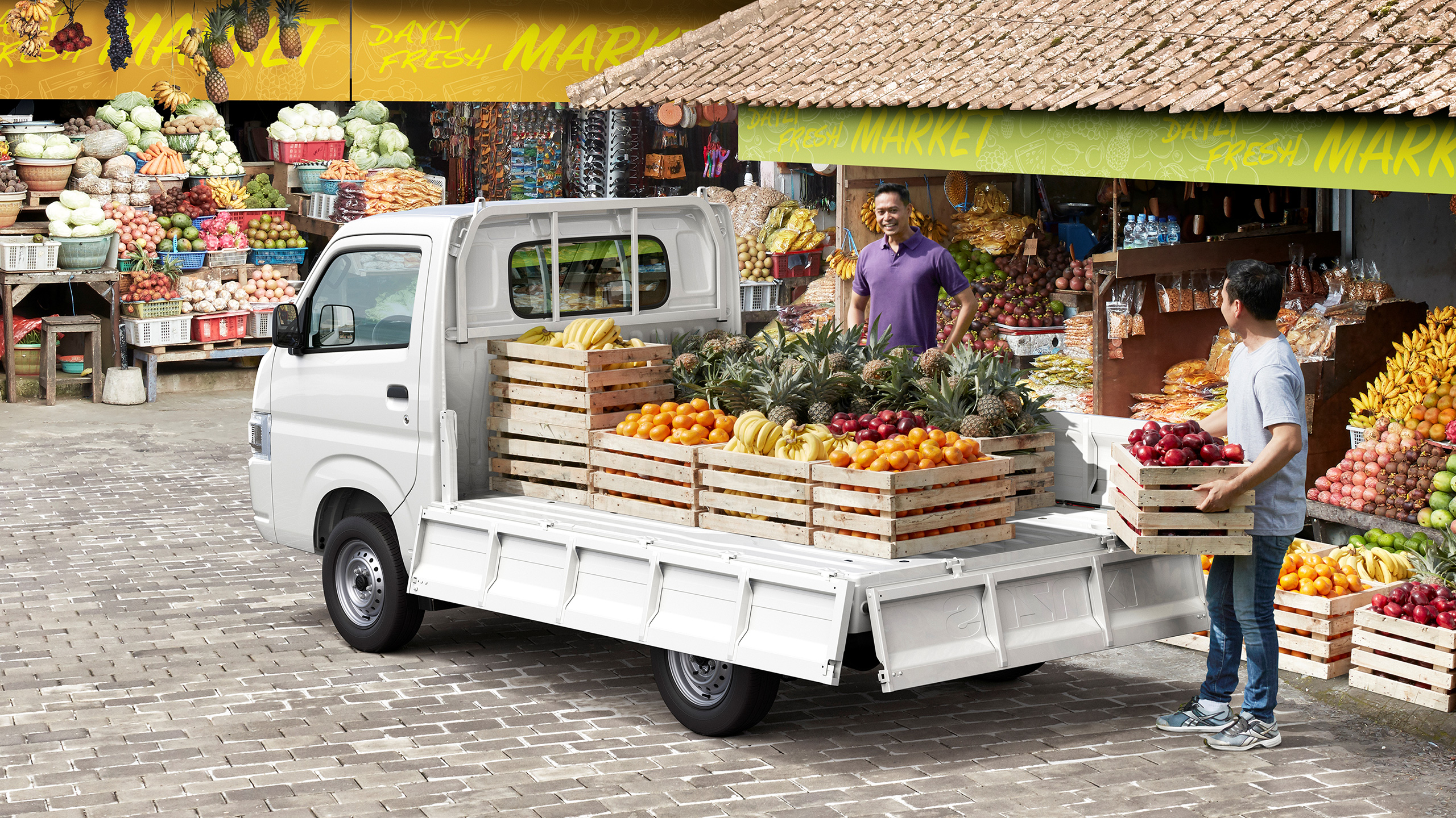 Carry-parked-in-front-of-the-fruit-market-and-a-man-is-loading-many-kinds-of-fruit-on-its-bed